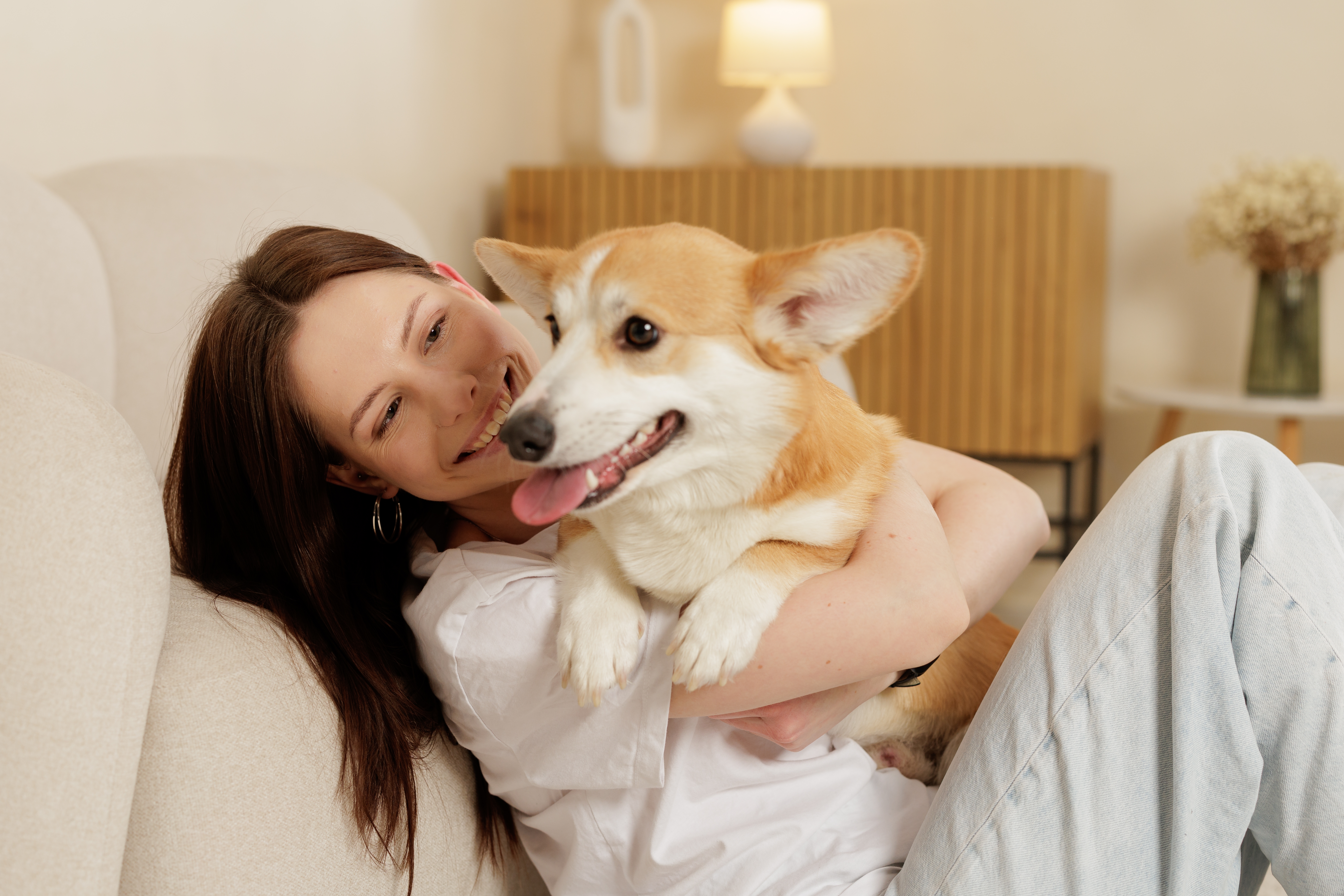 A smiling pet owner relaxing at home with her dog